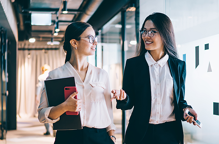 Two female coworkers walking down hallway