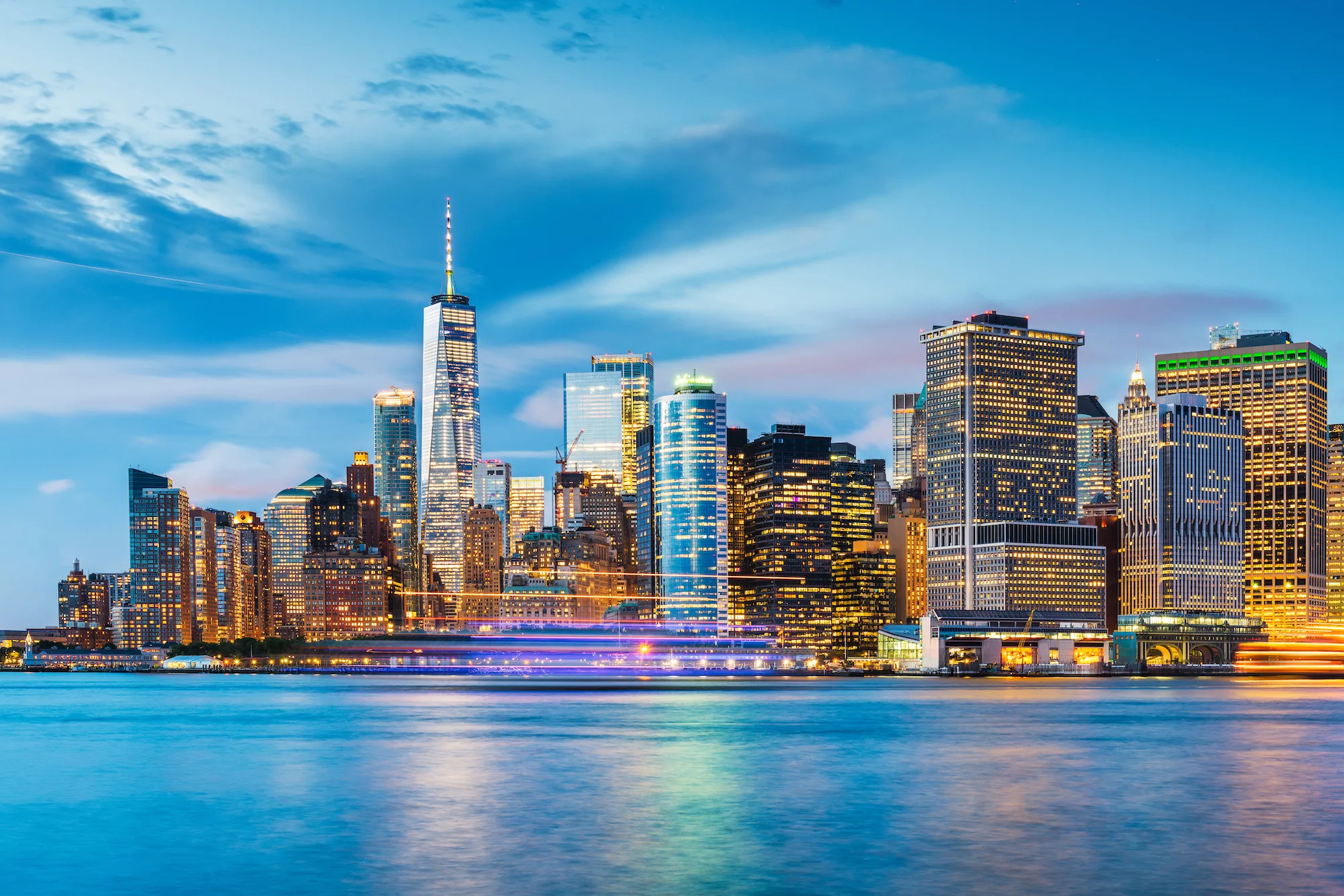 New York, New York, USA downtown city skyline at dusk on the harbor.