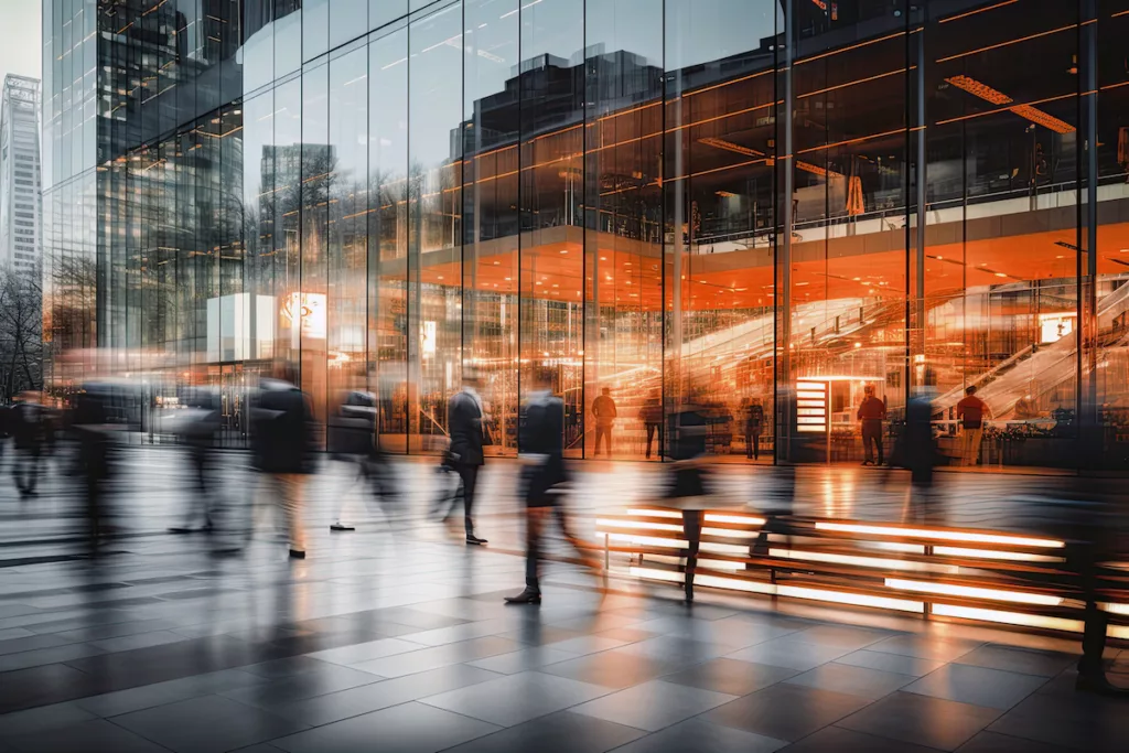 Blurred figures of business professionals strolling at an expo, conference, or within a contemporary hall.