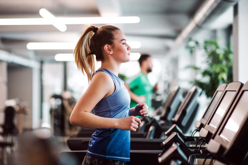 A portrait of young girl or woman doing cardio workout in a gym.