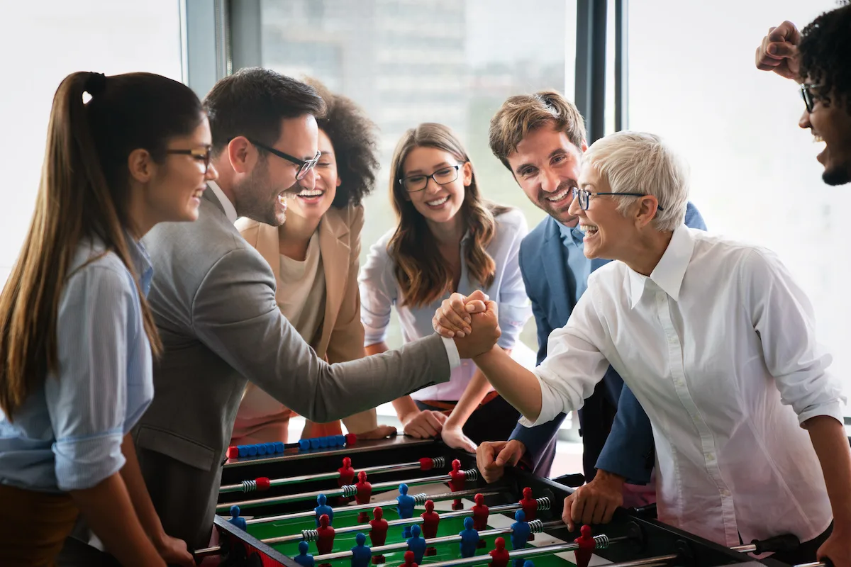 Employees playing table soccer indoor game in the office during break time to relieve stress from work