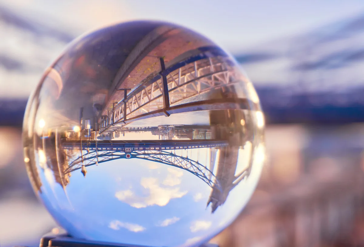 Tower Bridge through a crystal ball on a sunny day with blue sky in London. lens sphere