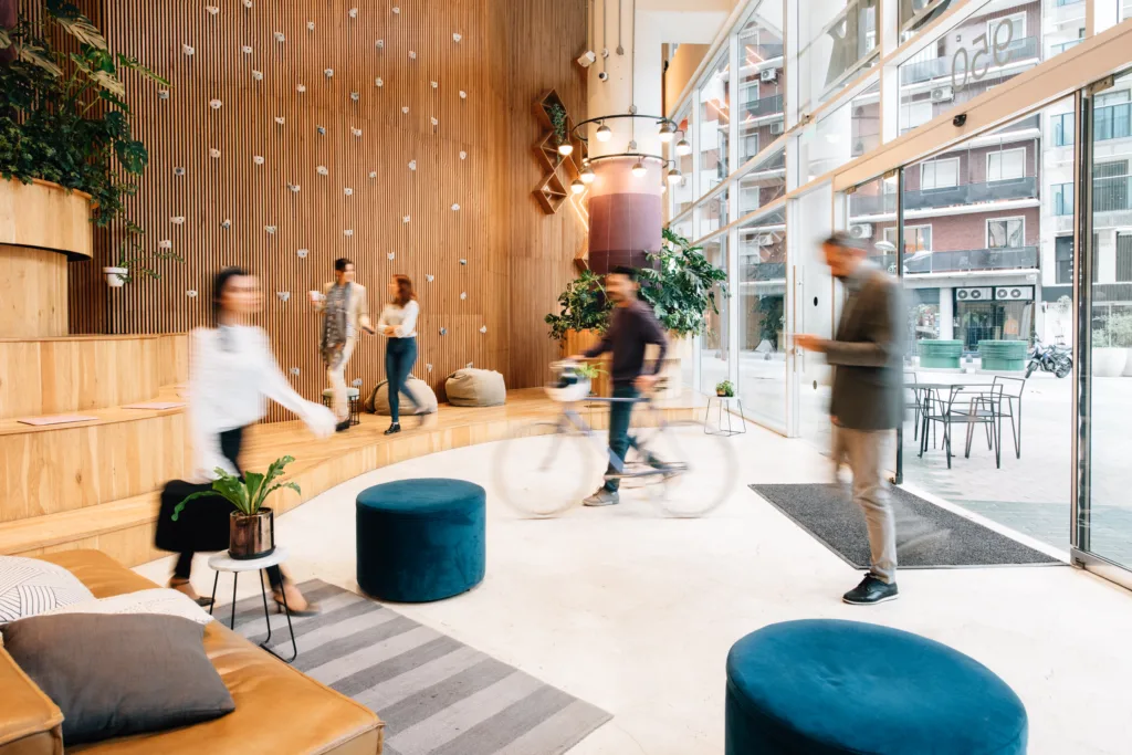 People moving quickly in different directions across a well lit office lobby.