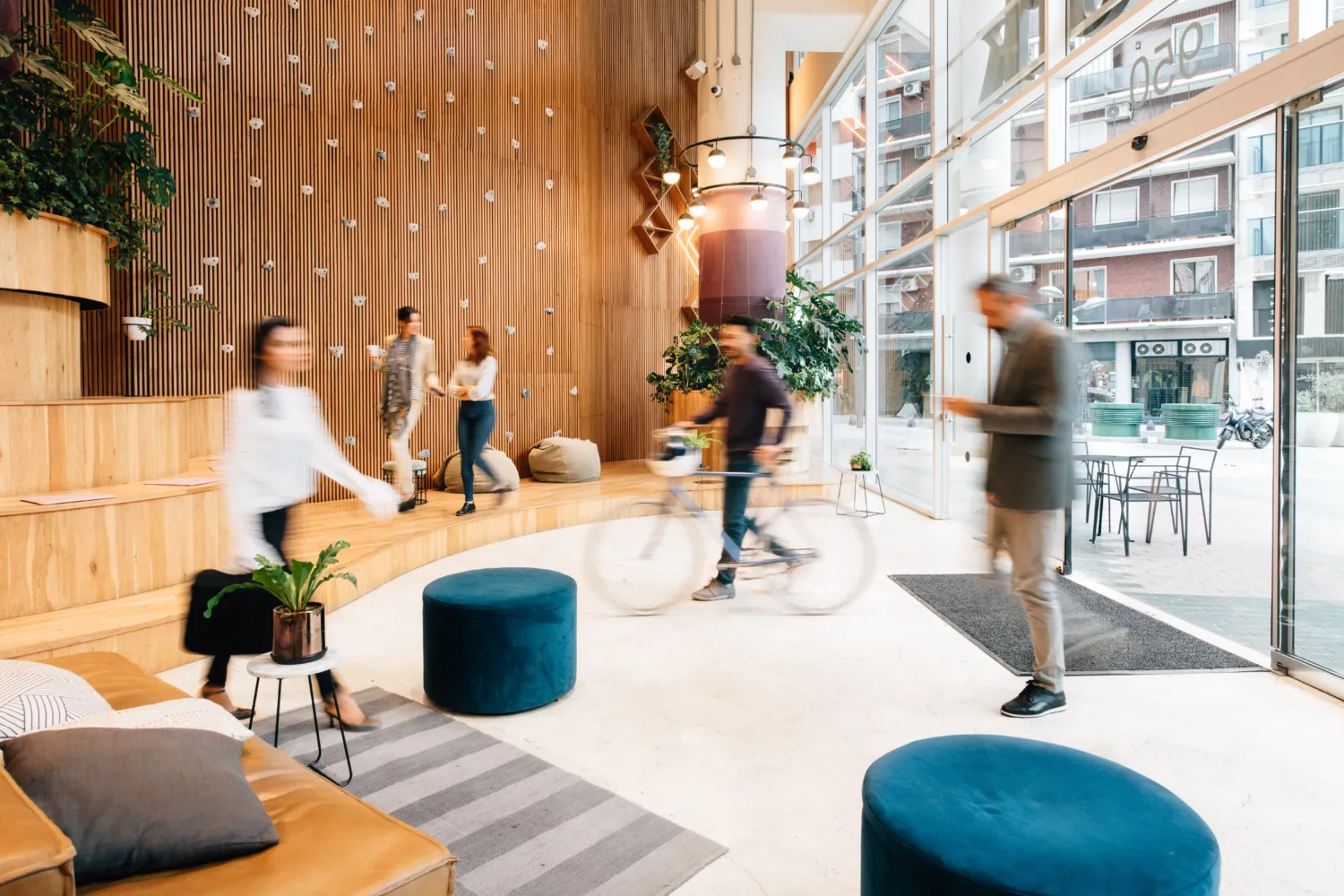 People moving quickly in different directions across a well lit office lobby.